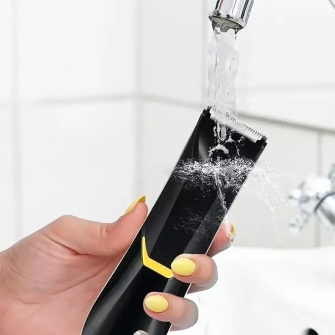 Hand holding a waterproof DENX electric trimmer under running water for cleaning